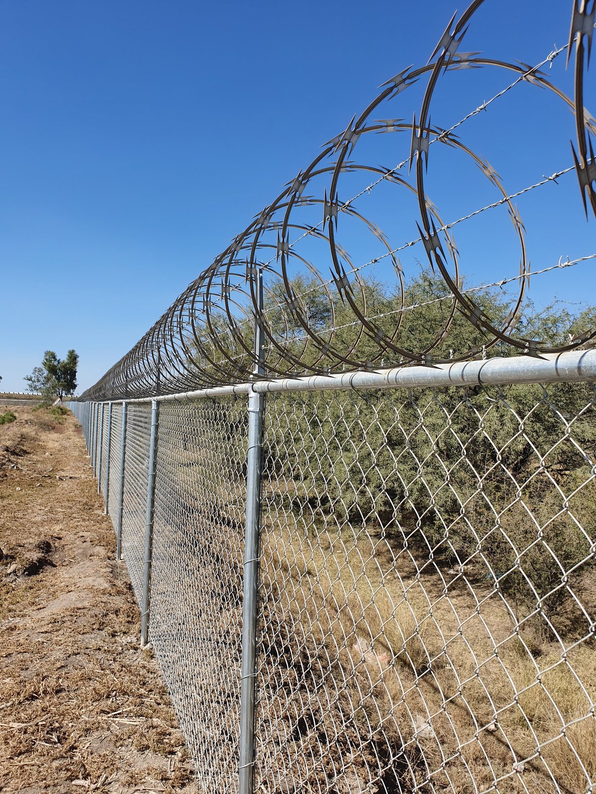 Cerca de malla ciclónica coronada con concertina y alambre de púas en instalación de seguridad perimetral en León, Guanajuato